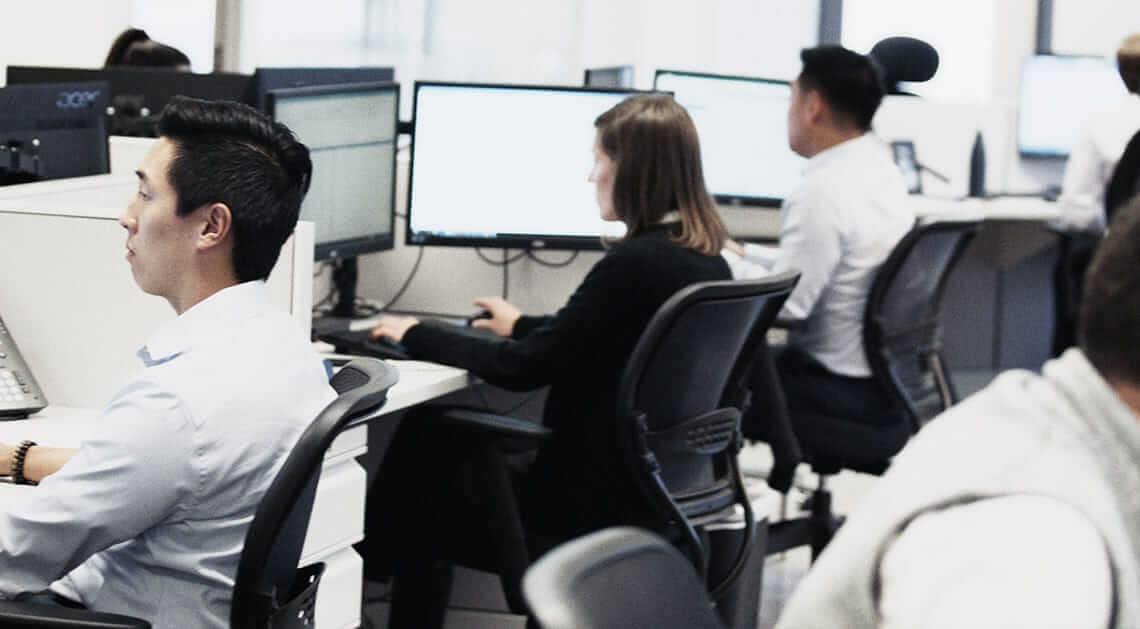 open plan office with several office workers sitting at desks working on computers