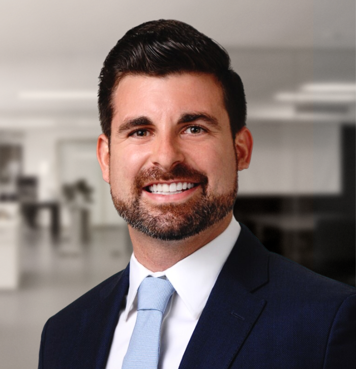 Portrait of a bearded man wearing a blue tie and dark jacket