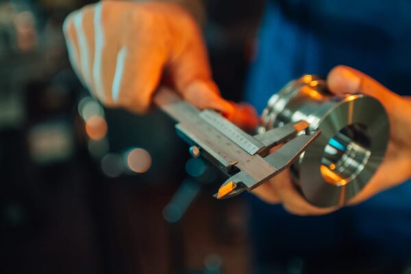 Worker measuring a metal part with a caliper