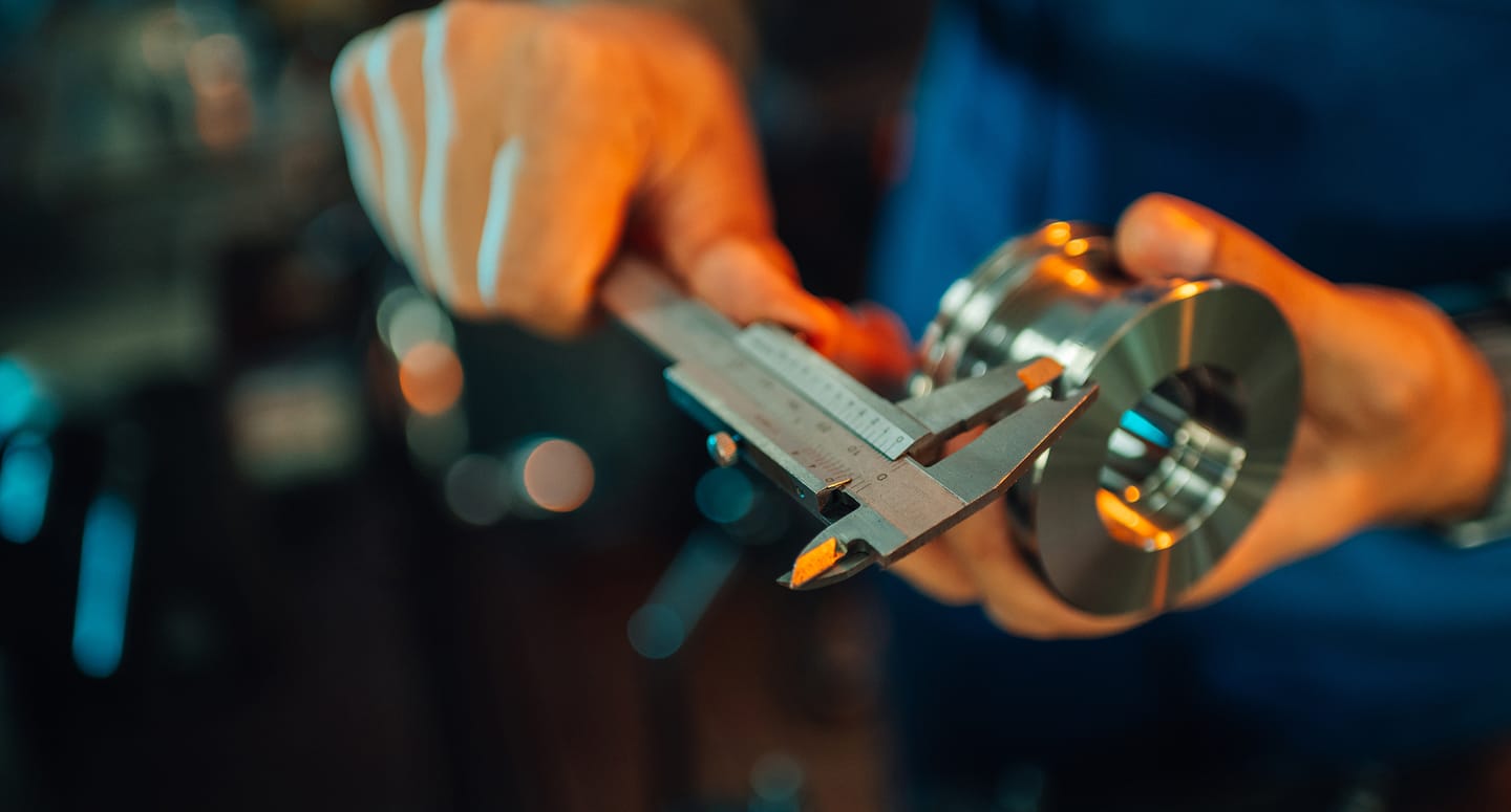 Worker measuring a metal part with a caliper