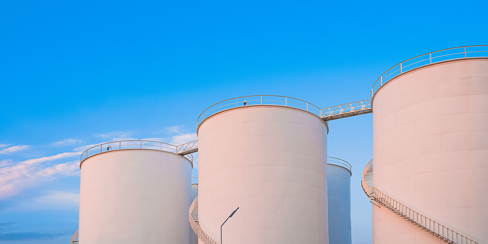 Group of chemical storage tanks against a bright blue sky