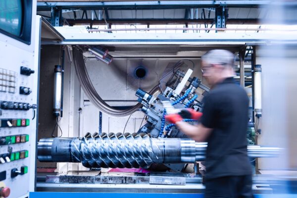 A worker inspecting a large metal lathe machine