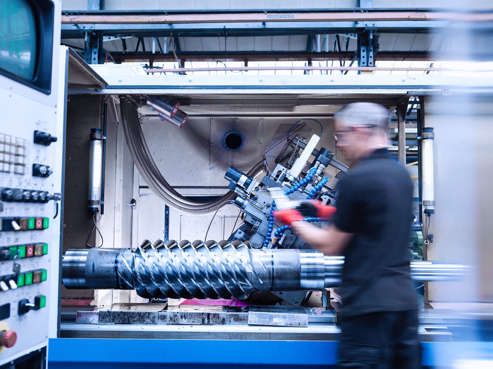 A worker inspecting a large metal lathe machine