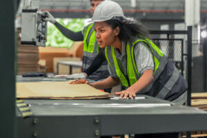 Technician inspecting a machine in a cardboard factory